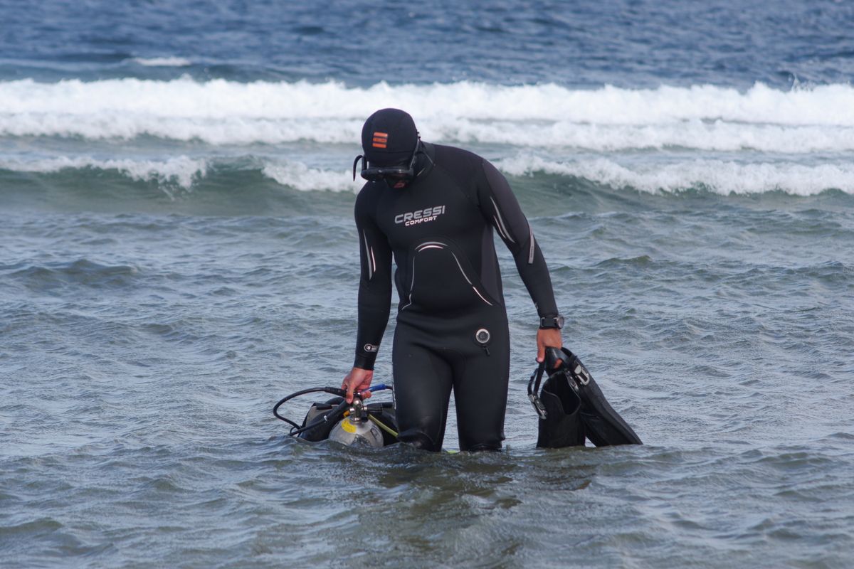 Diver entering the water from the beach through the surf
