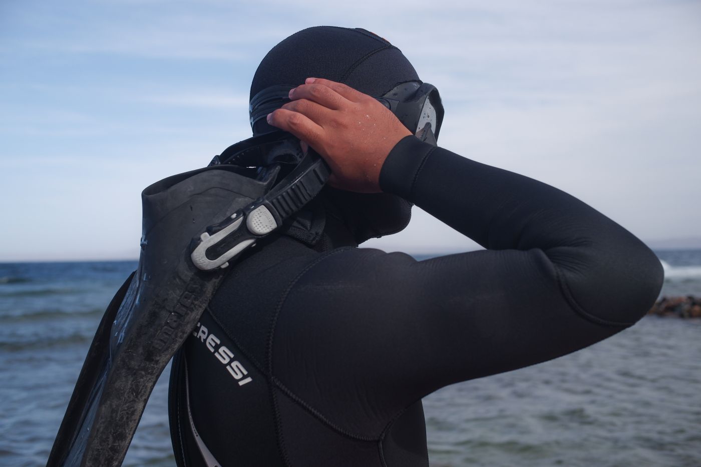 Diver adjusting a snorkeling mask beside the ocean