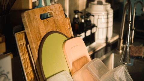 A well-organized kitchen sink area featuring cutting boards and storage containers in a cozy setting.