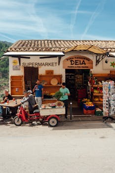 Vibrant street view of people and goods outside Supermarket Deia on a sunny day.