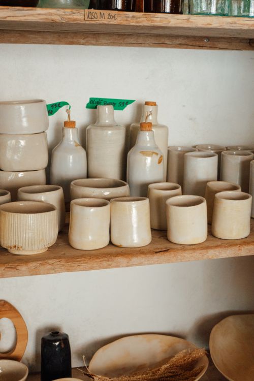 Free Beautiful collection of rustic ceramic pottery displayed on wooden shelves in a cozy indoor setting. Stock Photo