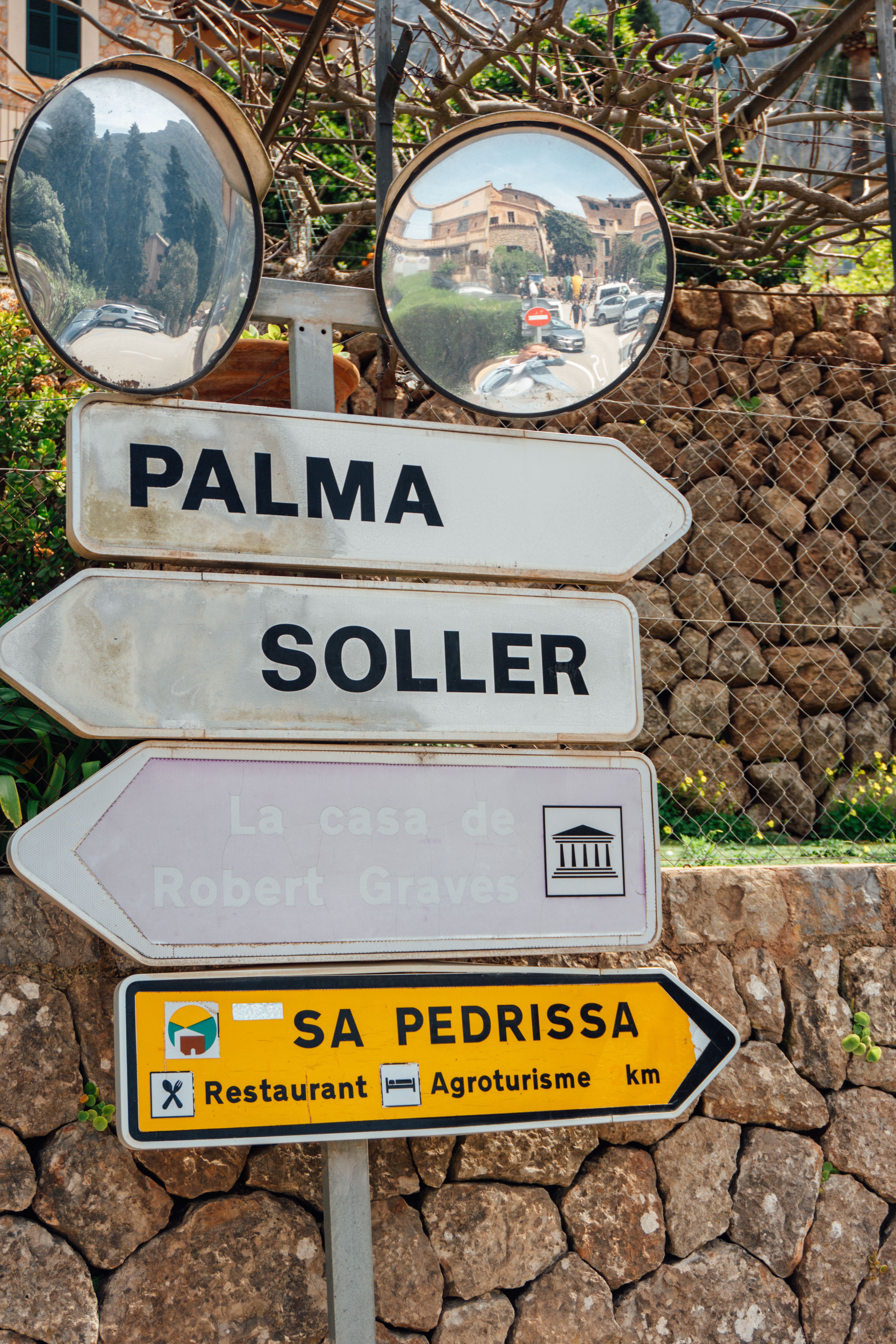 Signpost in Mallorca directs to Palma, Soller, and Sa Pedrissa, with mirrors reflecting scenery.