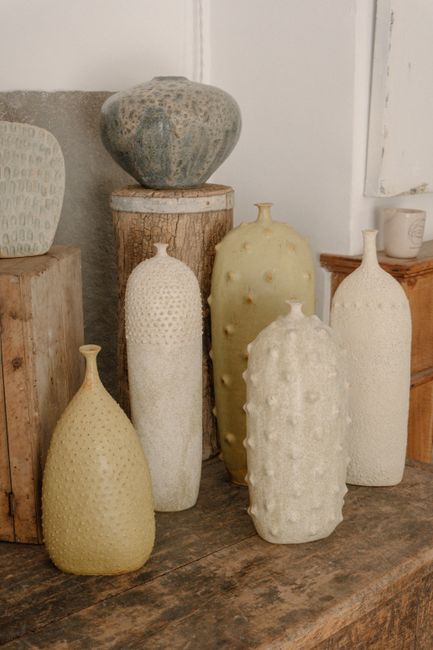 A collection of unique ceramic vases displayed on a rustic wooden surface, showcasing artistic design and texture.