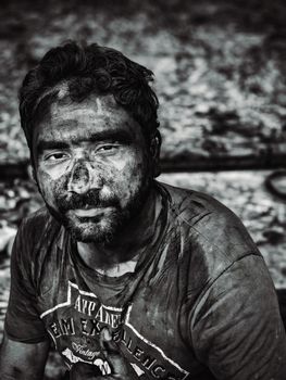 A gritty black and white portrait of a man with dirt-covered face depicting hard work.