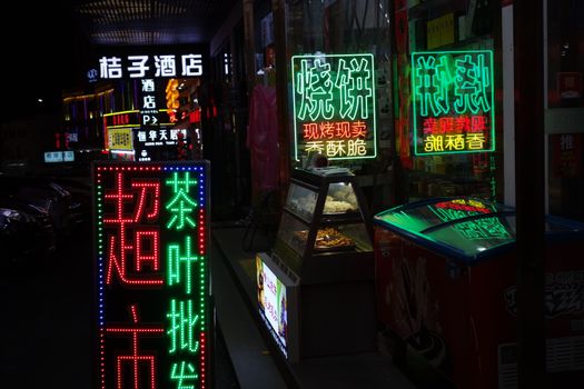 Colorful neon signs illuminate a bustling night market, showcasing a lively urban atmosphere.