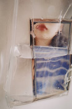 Creative abstract image capturing a face's reflection in water through glass with artistic distortion.
