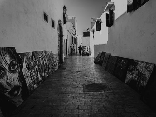 Free Artistic alleyway with paintings in a narrow urban street, capturing city life. Stock Photo
