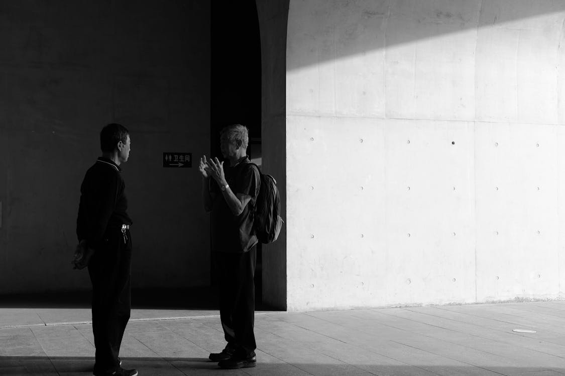 Gray-scale Photography of Two Men Facing Each Other While Standing