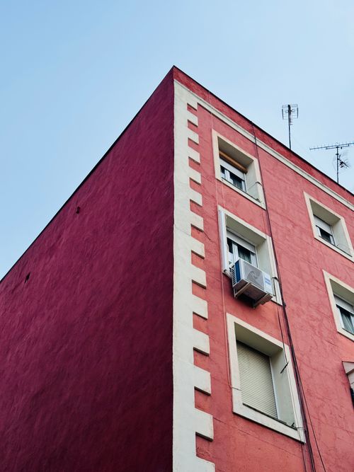 Free Corner view of vibrant urban building with antennas, air conditioner against a clear sky. Stock Photo