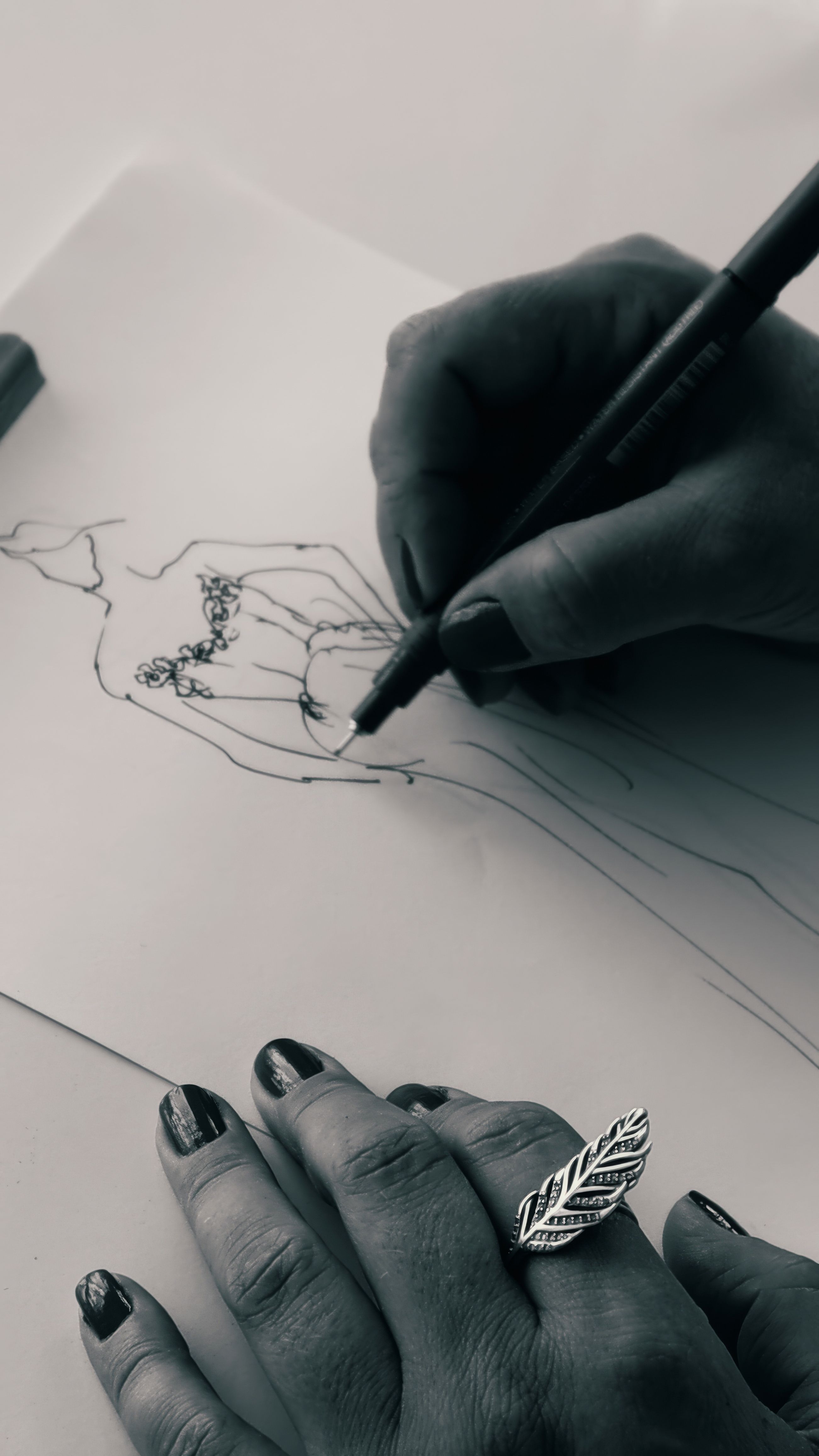 A detailed sketch of a bridal gown being drawn by hand, highlighting artistic creativity.