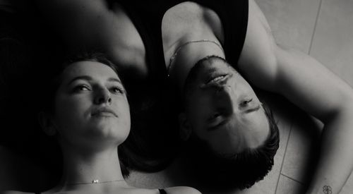 Free Intimate black and white portrait of a couple lying on the floor, expressing tenderness and serenity. Stock Photo