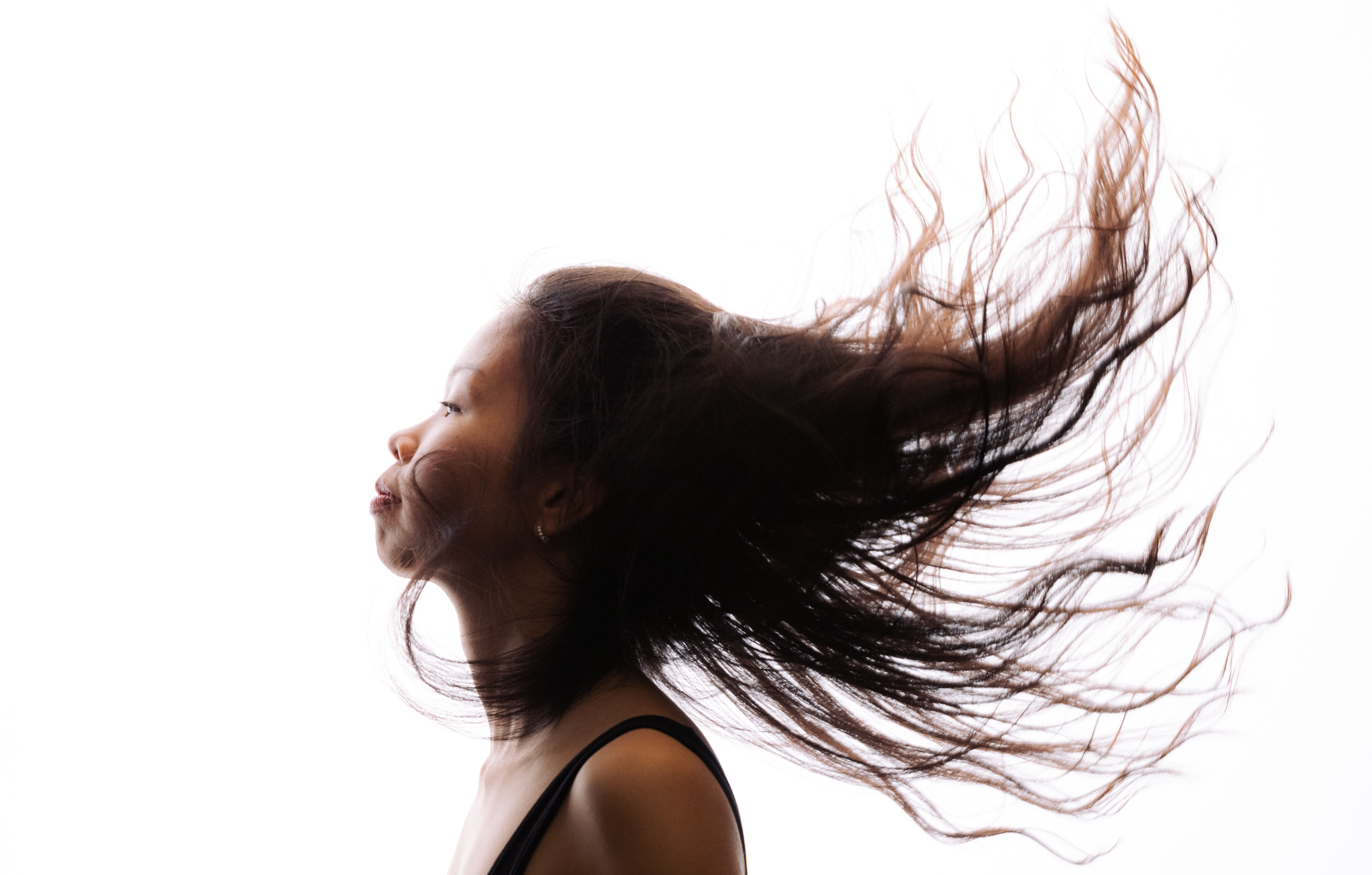 A high-contrast profile of a woman with her hair flowing, showcasing movement and expression.