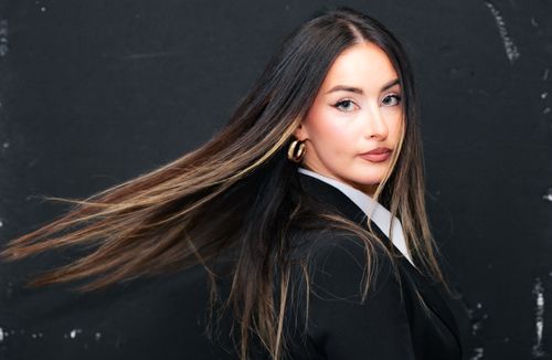 Free Portrait of a stylish woman with long flowing hair and a serious expression in Munich. Stock Photo