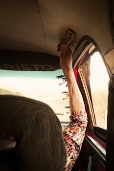 Close-up of an elderly hand gripping a car handle inside a vehicle in sunny Brazil, showcasing a rustic vibe.