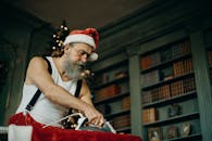 在节日图书馆里，大胡子男人打扮成圣诞老人熨烫衣服，并布置圣诞装饰