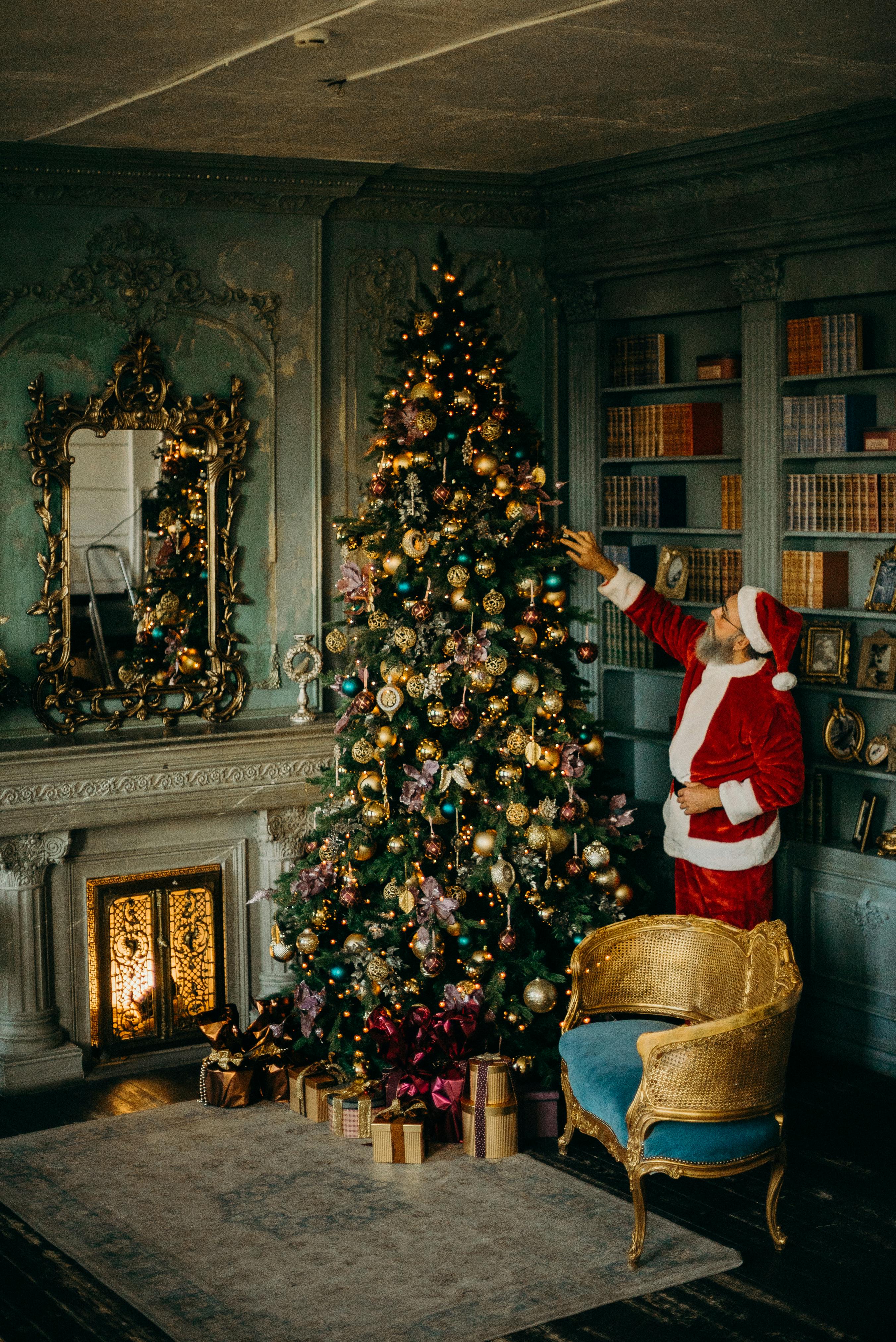 Santa Claus standing beside a Christmas tree. | Photo: Pexels