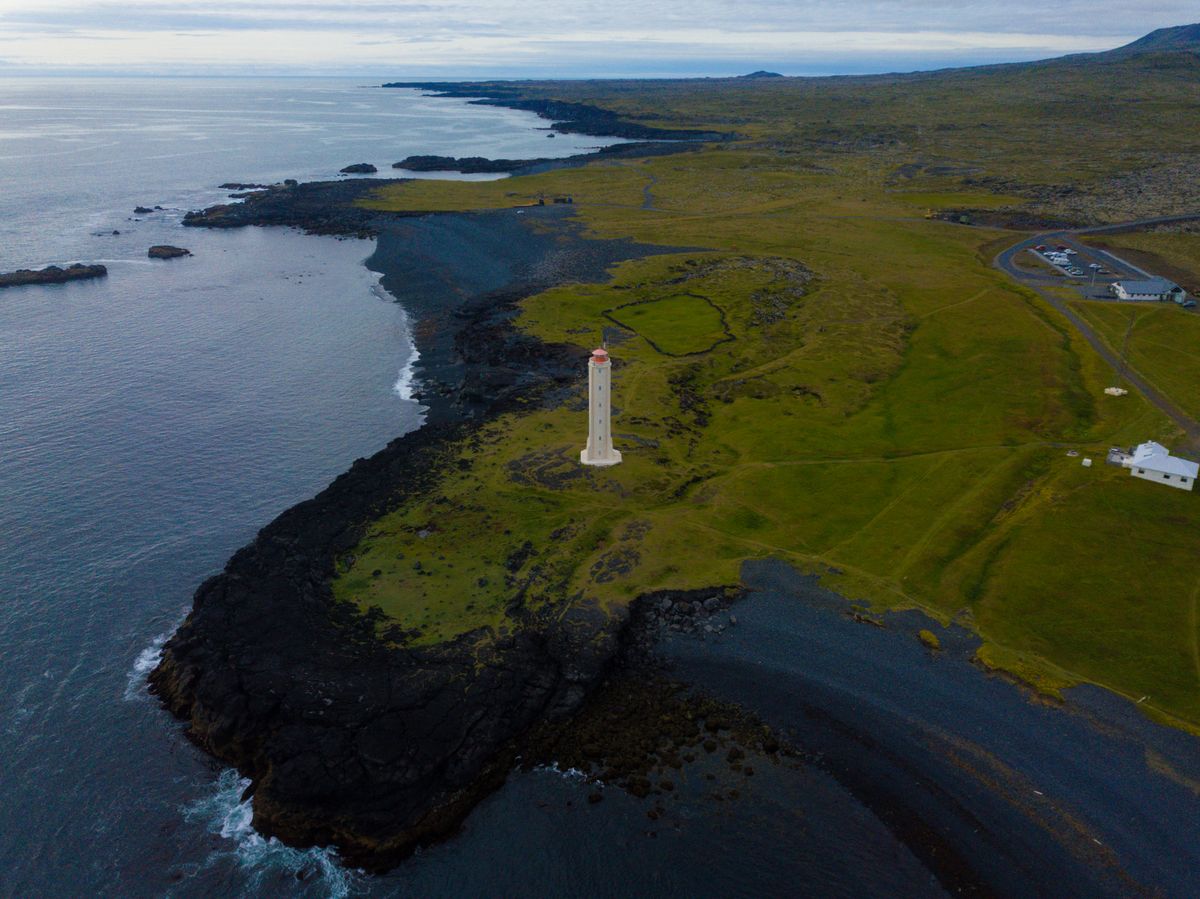 A stunning aerial shot showcasing a solitary lighthouse on Iceland's rugged coastline.