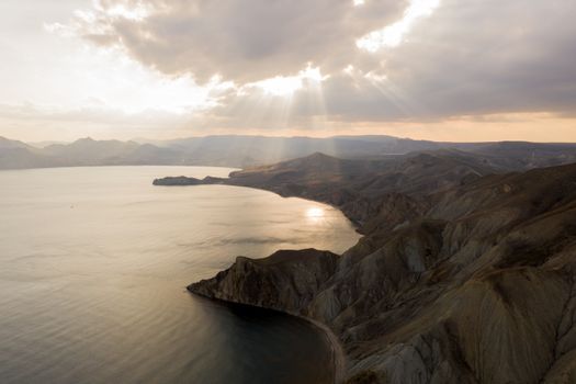 Aerial view of rugged coastline and mountains in Koktebel during sunset.