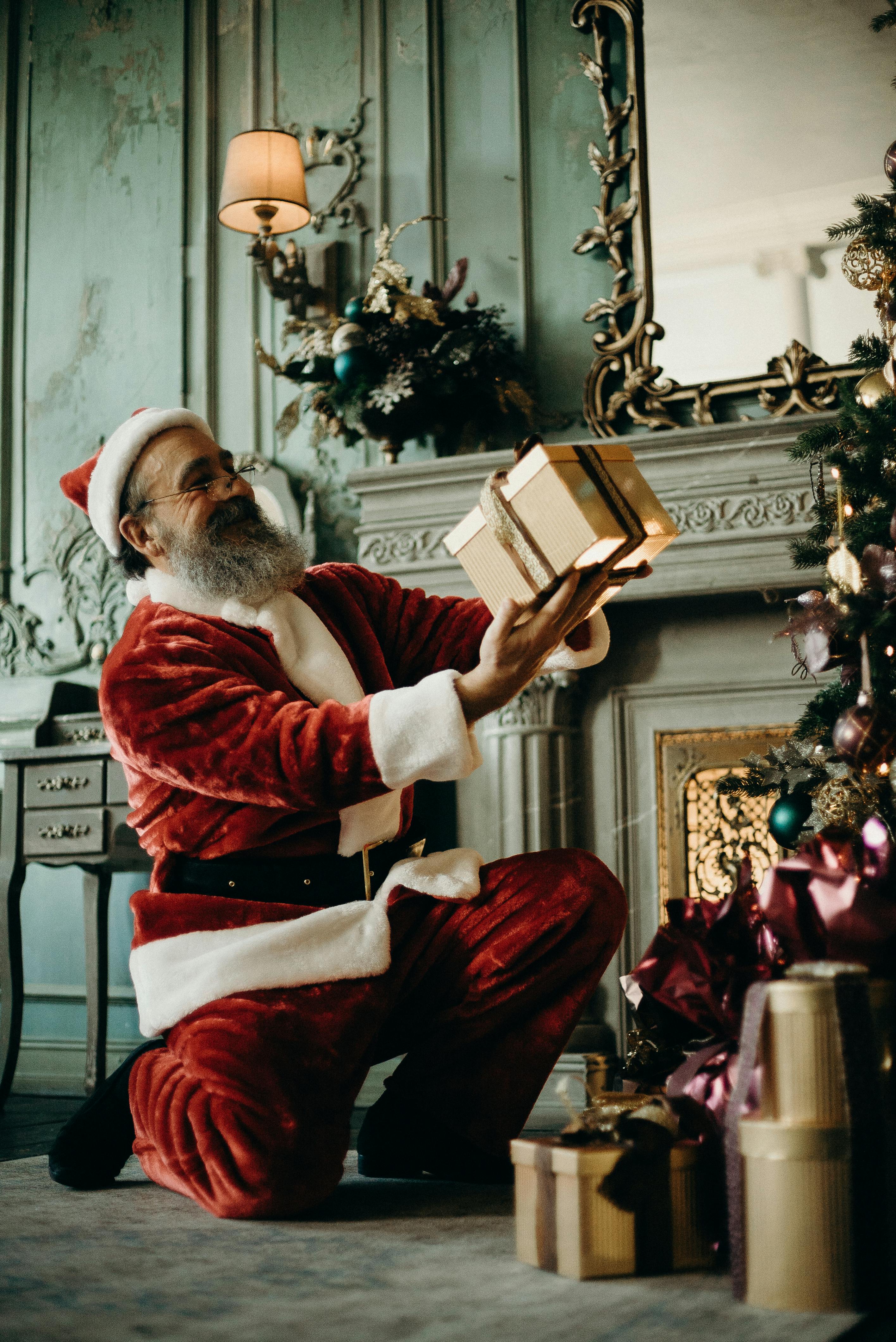 Santa Claus holding a gift box. | Photo: Pexels
