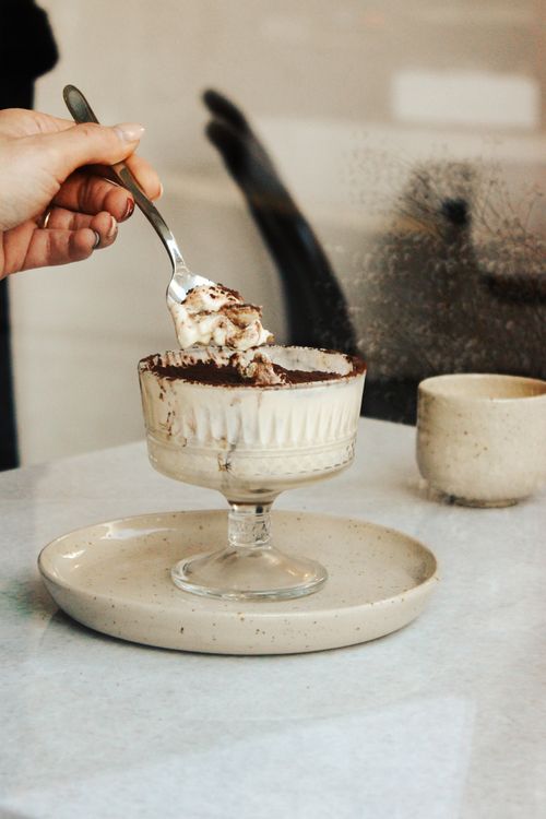 Free Delicious tiramisu dessert served in a glass cup on a table, ready to be enjoyed. Stock Photo