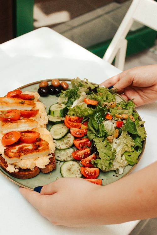 Free Vibrant plate of Mediterranean veggies and cheese toast served on a green dish, perfect for healthy eating. Stock Photo