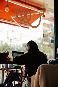 Group of adults working on laptops in a cozy indoor cafe setting.