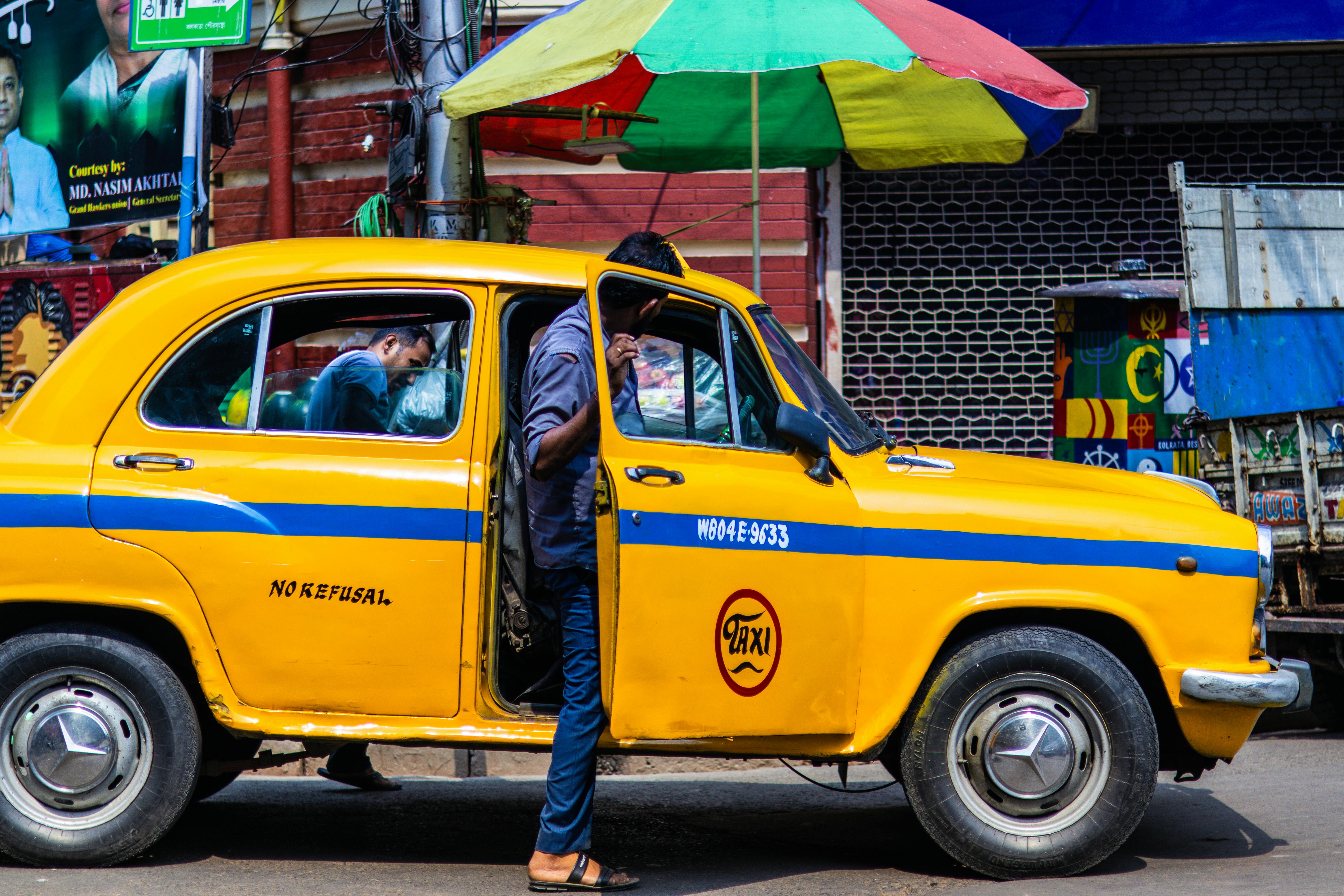 A vibrant yellow taxi on a bustling street in Kolkata, showcasing local life and culture.