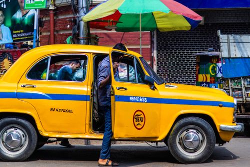 Free A vibrant yellow taxi on a bustling street in Kolkata, showcasing local life and culture. Stock Photo