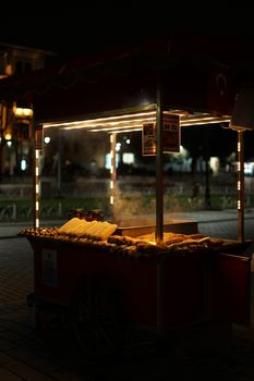 Dimly lit street food cart selling grilled corn at night in a city park.