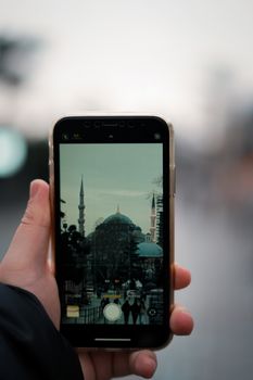 Smartphone photo of iconic mosque in blurred background, capturing cultural scene.