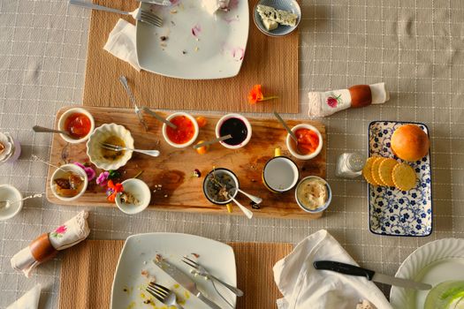 Overhead shot of a dining table with empty plates, various condiments, and utensils, creating a cozy post-meal scene.