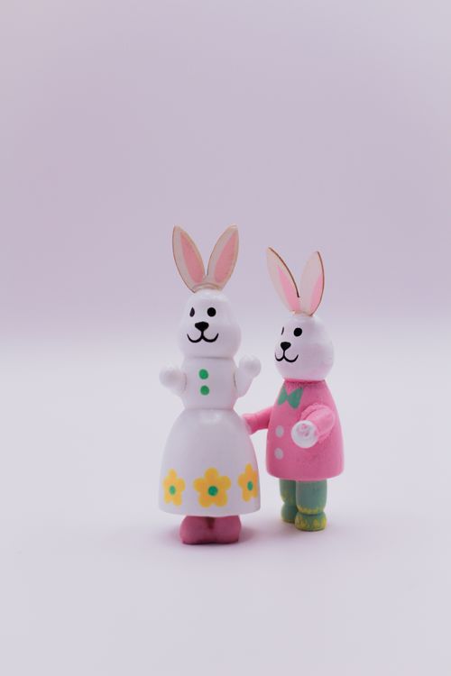 Free Charming Easter bunny figurines with colorful attire, set against a soft pastel backdrop, embodying Easter joy. Stock Photo