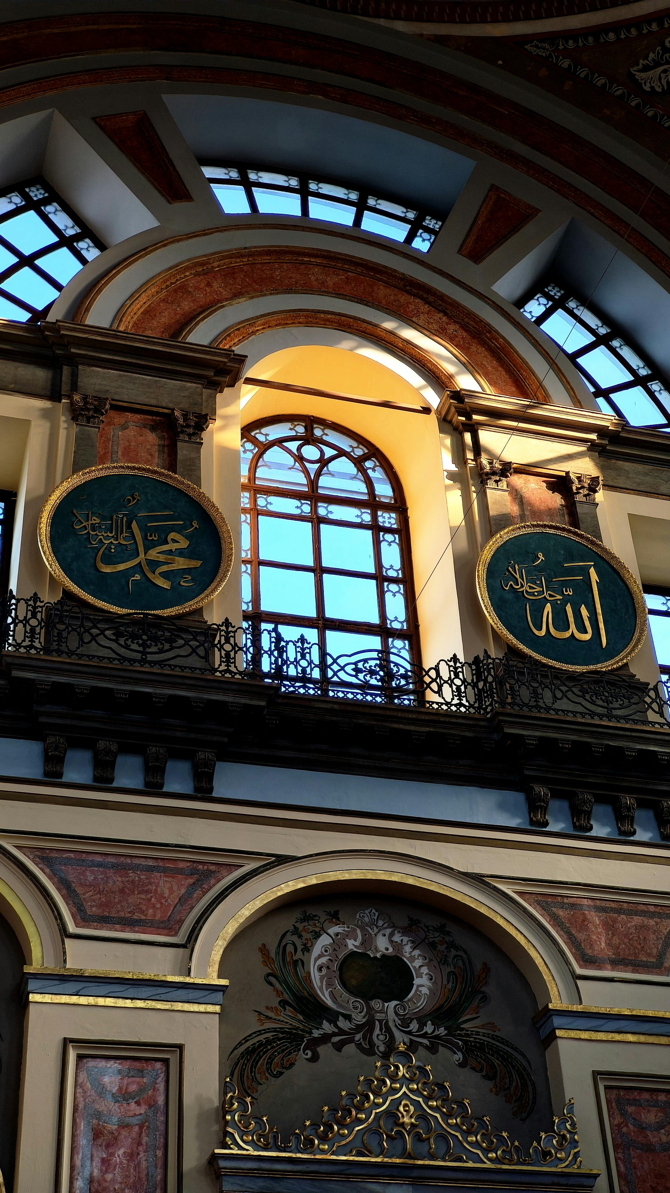 Stunning interior of an İstanbul mosque featuring intricate Islamic calligraphy and stained glass windows.