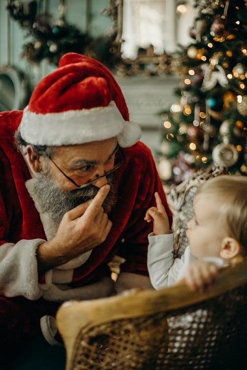 Man in Red Santa Claus Costume Standing Beside Toddler