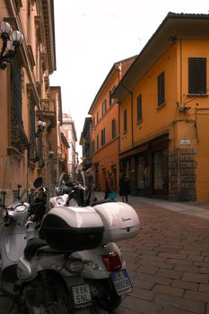 Charming narrow street in Italy with scooters and historic architecture, capturing local life.