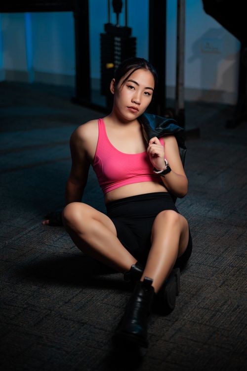 Free Young woman in sporty attire sitting on gym floor, resting between workouts. Stock Photo