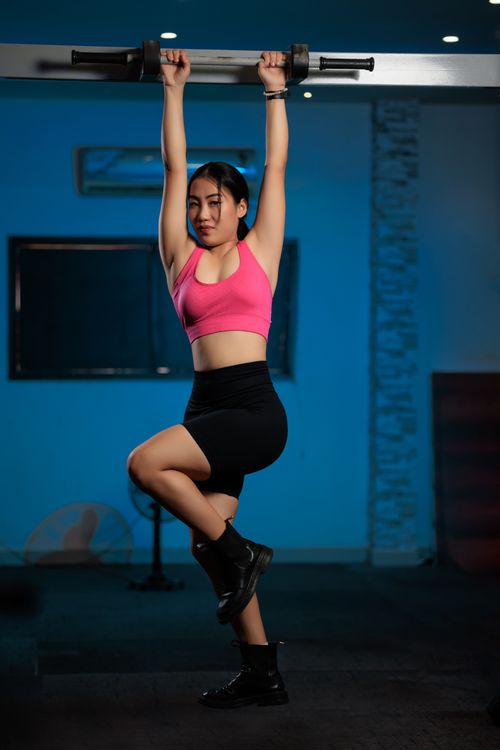 Free Adult woman exercising by hanging from a bar in a gym. Fitness and strength training concept. Stock Photo