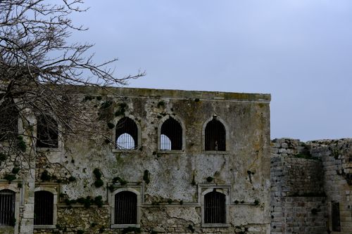Free Weathered fort wall with barred windows in Sinop, showcasing rugged architecture under an overcast sky. Stock Photo