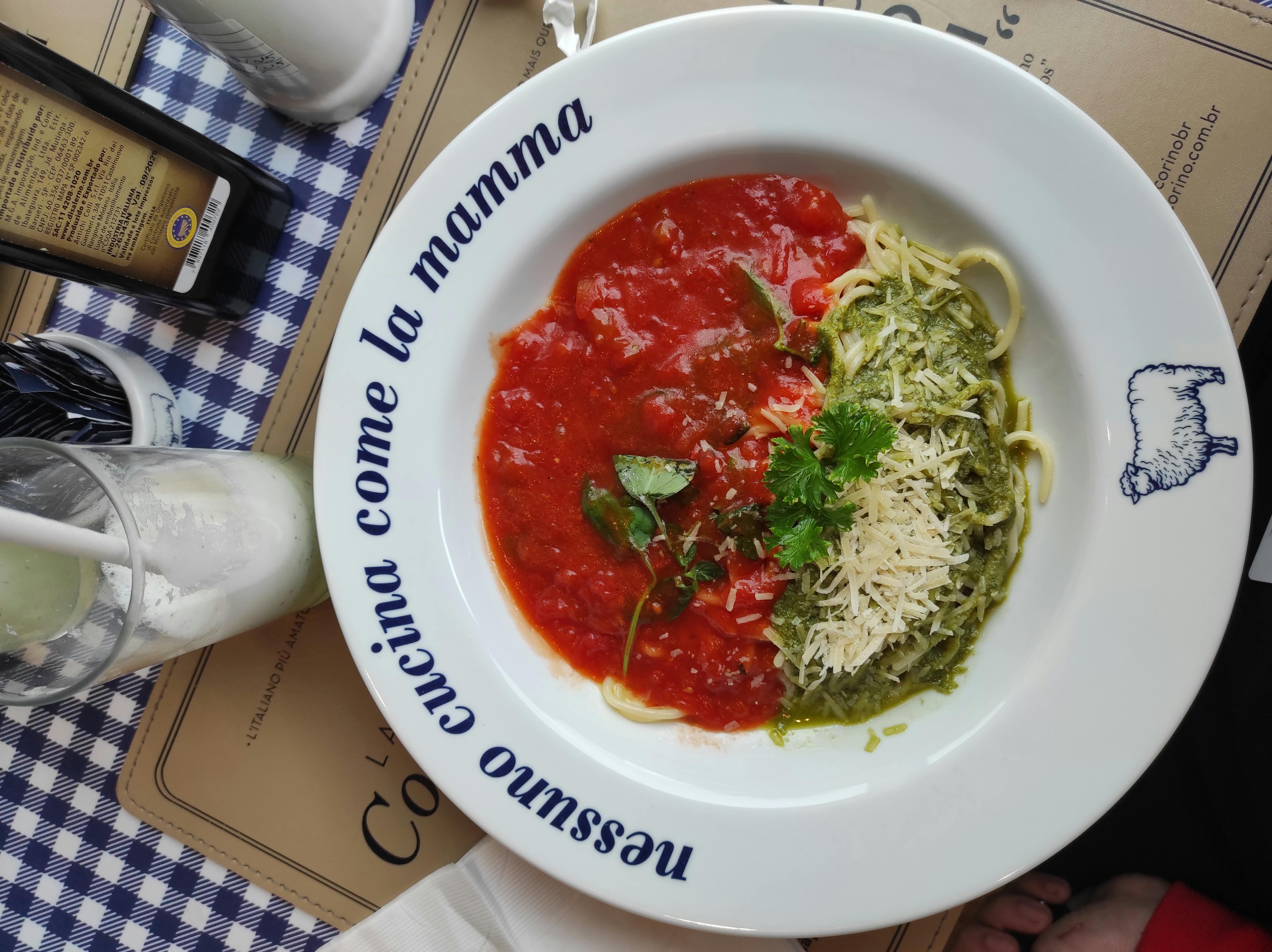 Delicious spaghetti with vibrant tomato and pesto sauce served in a classic plate.