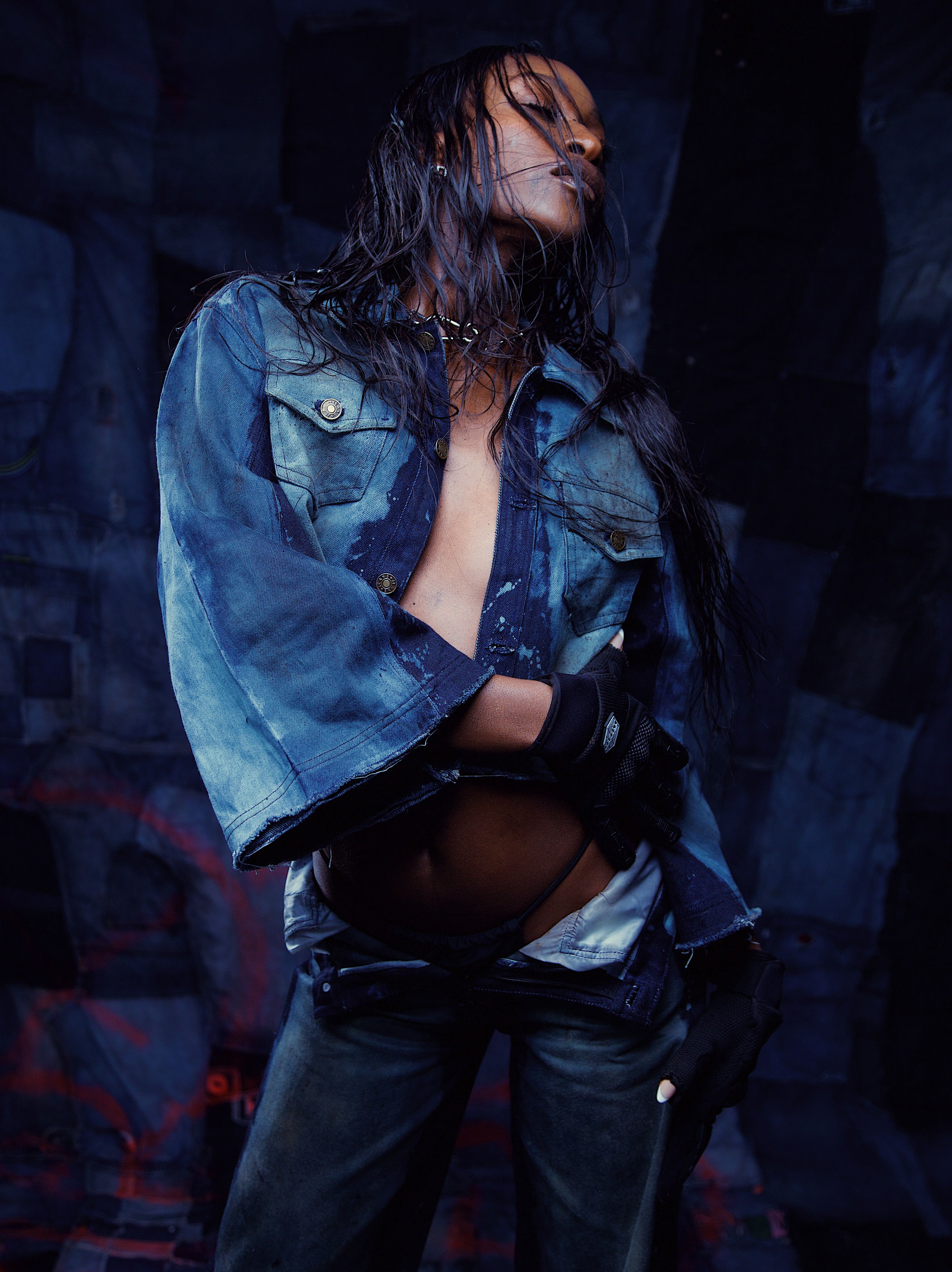 Stylish woman posing confidently in denim jacket and pants, exuding edgy fashion mood.