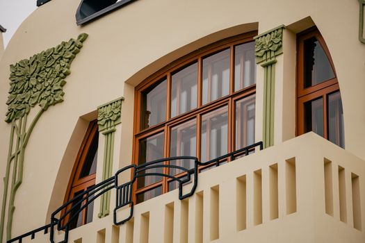Art Nouveau architectural detail of a balcony with floral decor and wooden windows.. nouveau, architectural, detail