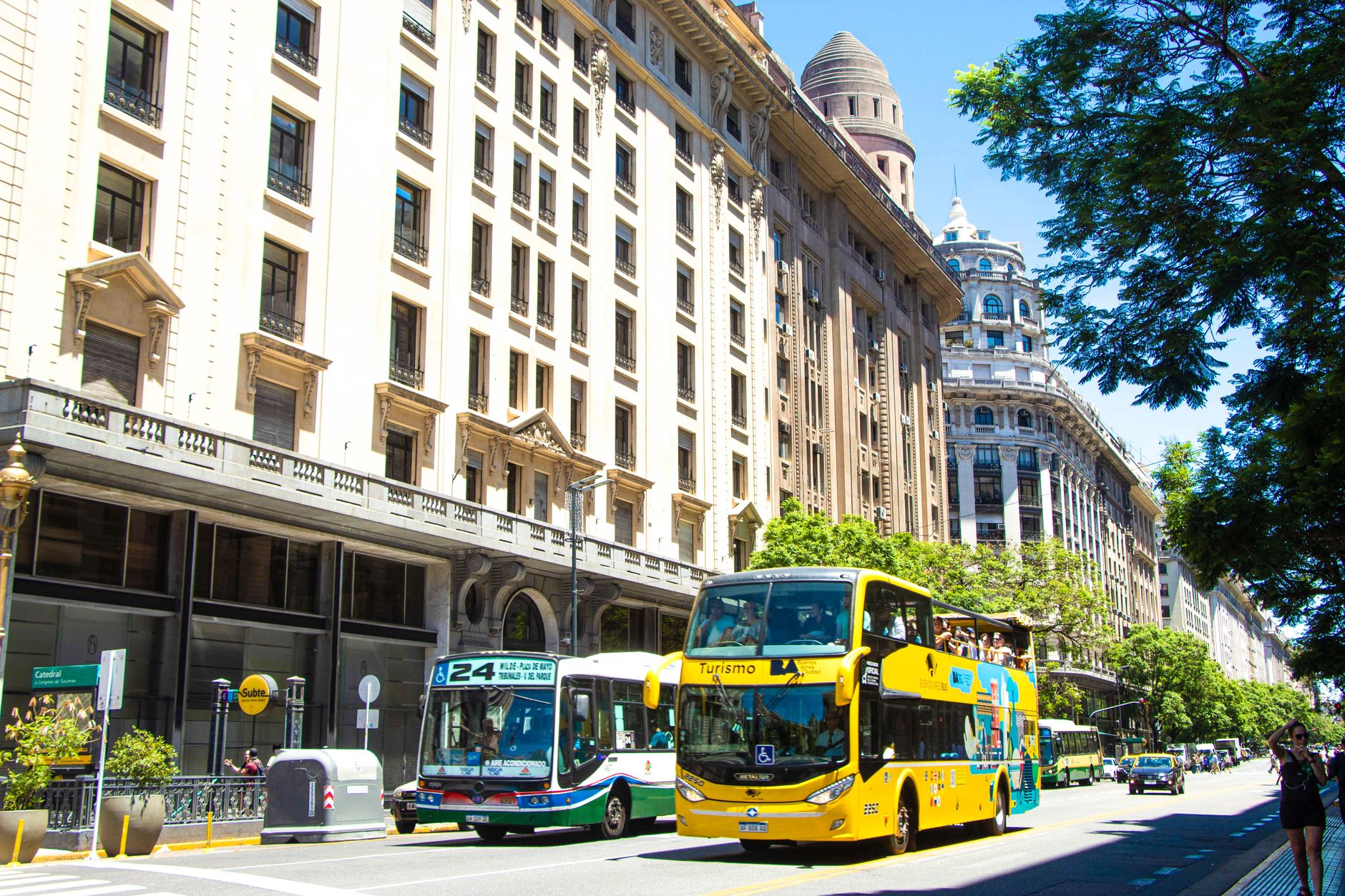 Vibrant daytime view of busy street with tour buses in Buenos Aires, Argentina.