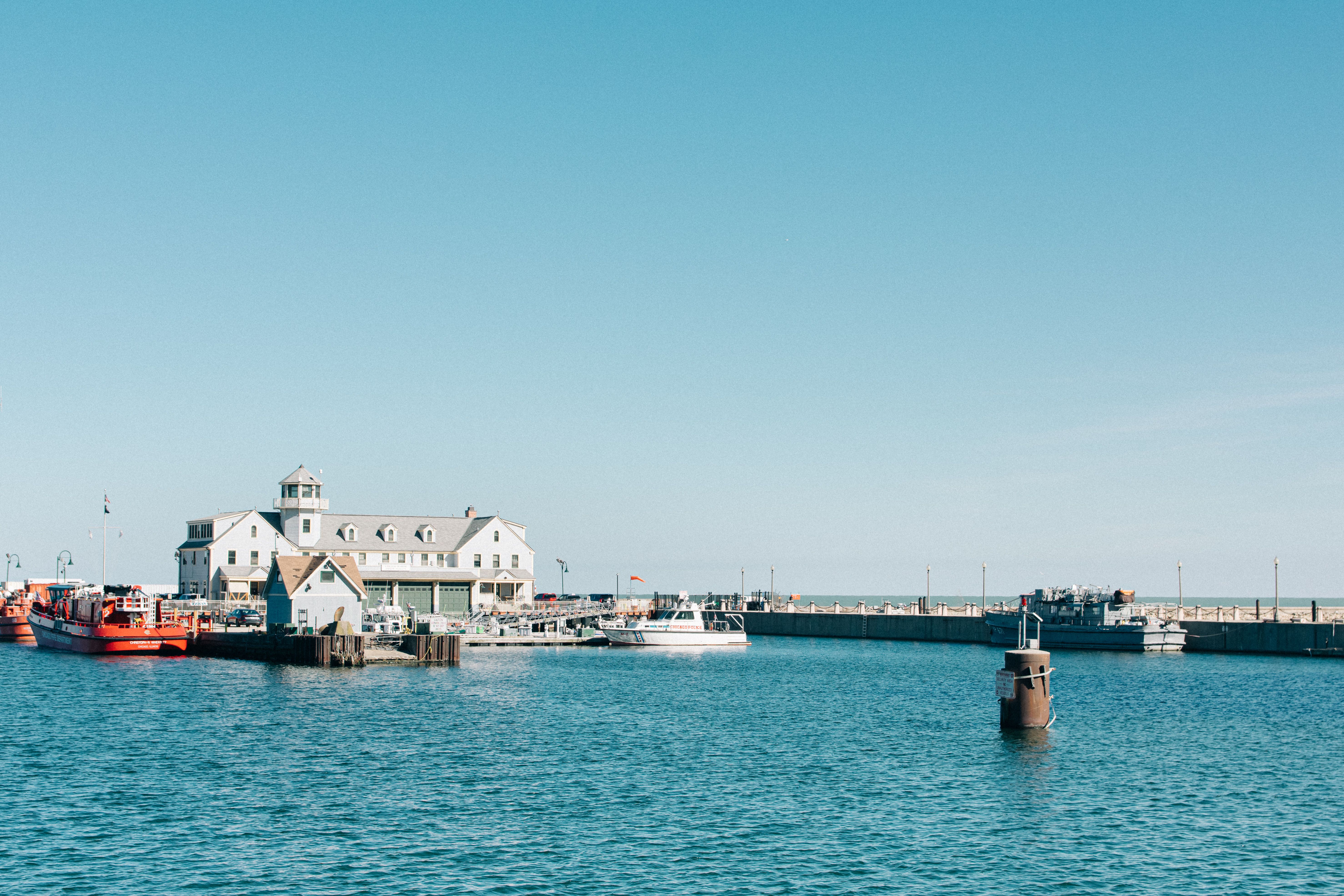 A calm Chicago harbor with boats and buildings under a clear blue sky, perfect for a summer getaway.