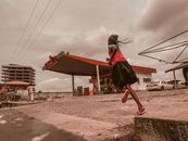 Woman Running Near Red and White Gasoline Station
