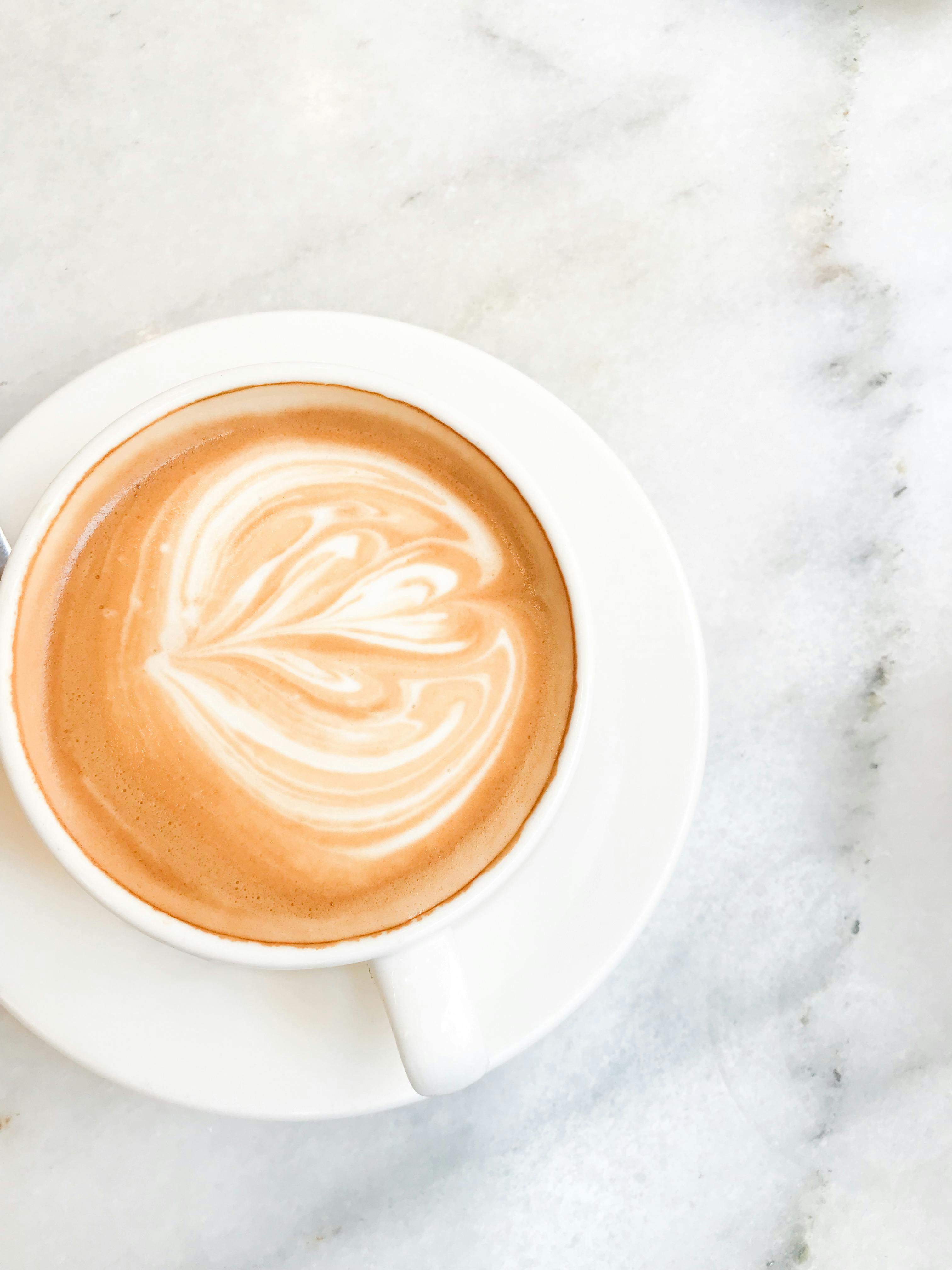 Captivating top-down view of a latte with heart latte art on a marble table.