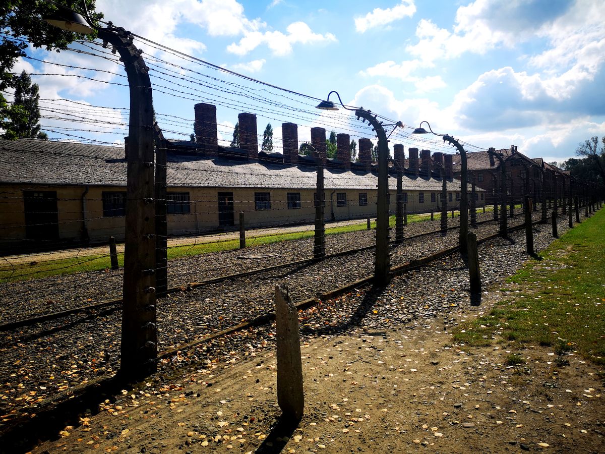 Barbed wire fencing at Auschwitz Birkenau with barracks behind