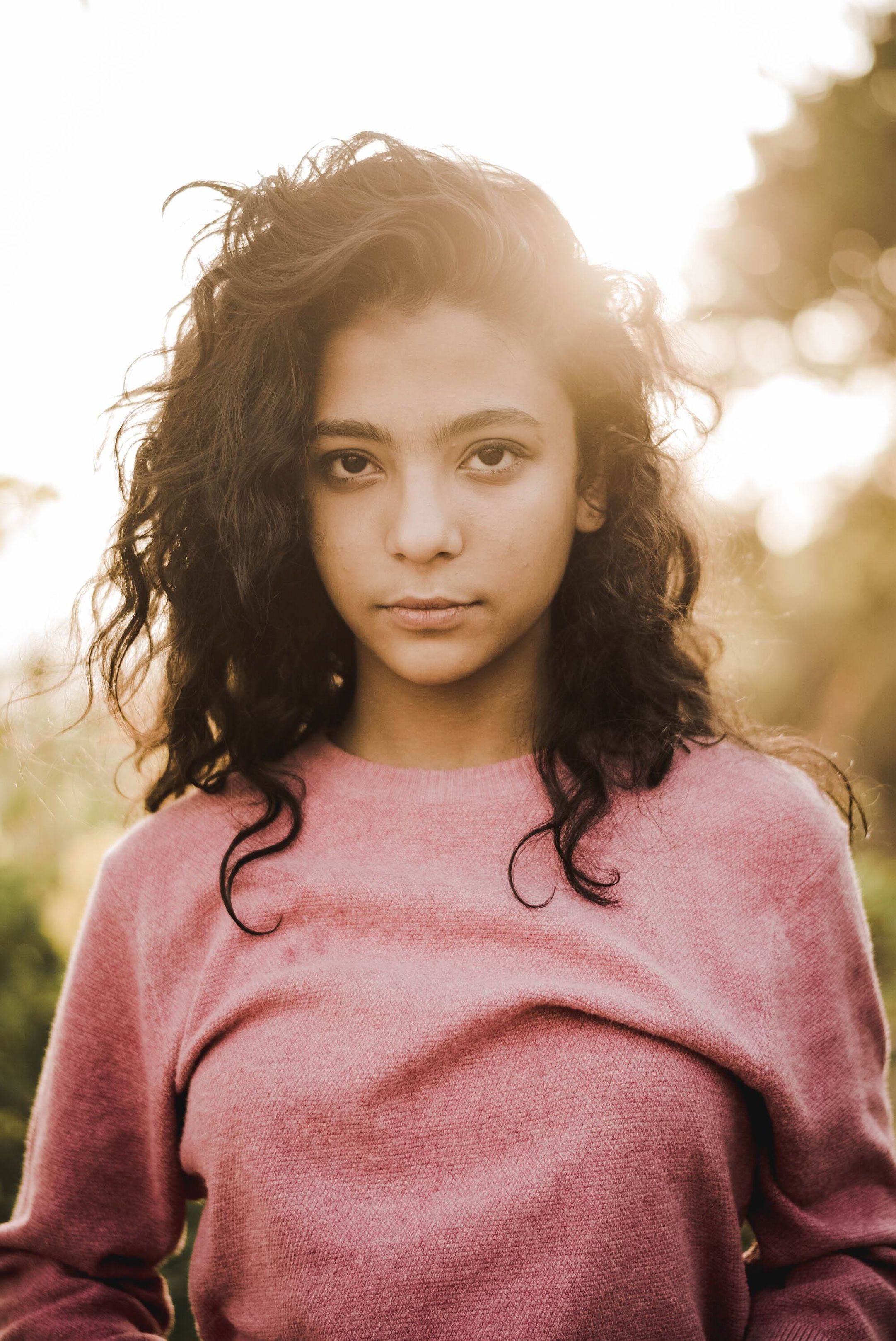 Captivating portrait of a young woman with curly hair in warm evening light.