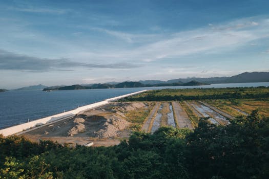A panoramic view of a coastal landscape in China showcasing water channels and greenery beneath a bright blue sky.