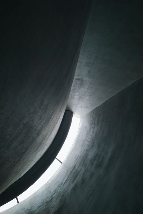 Free Curved concrete structure with natural light, creating a dramatic abstract architectural scene. Stock Photo
