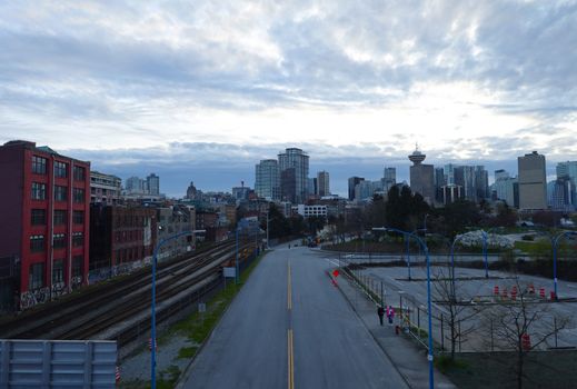 Explore Vancouver's beautiful skyline featuring high-rises and rail tracks under a cloudy sky.